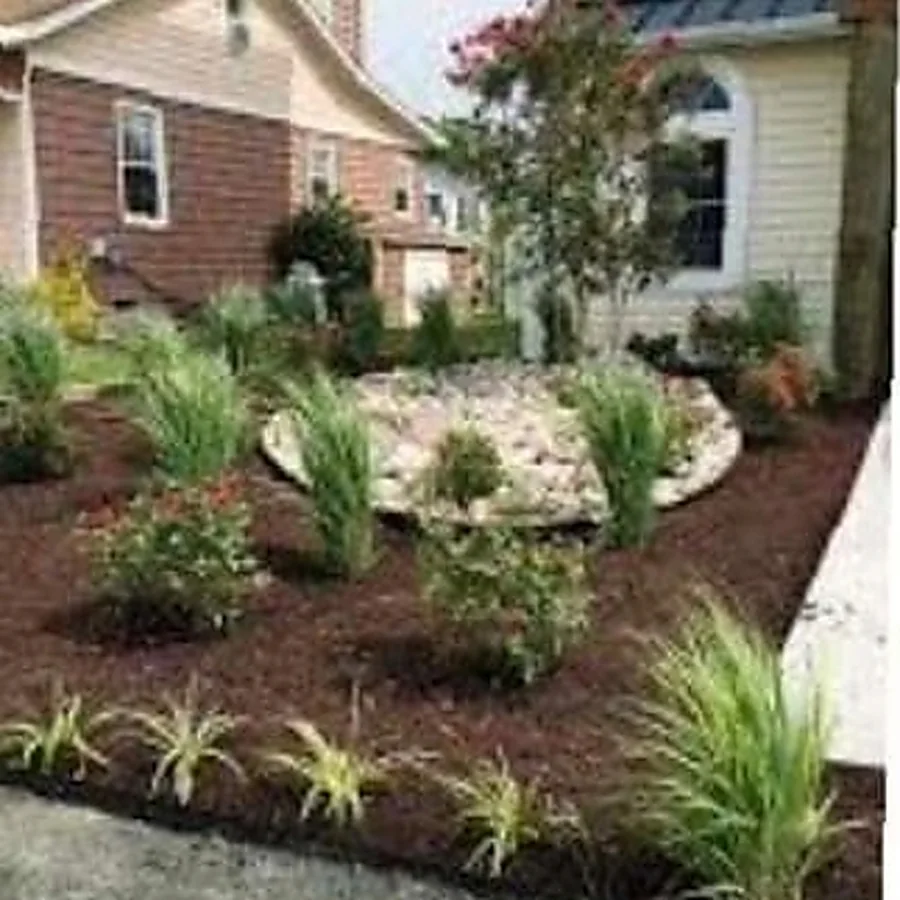 A new foundation planting with ornamental grasses, shrubs and a rock feature at a brick home