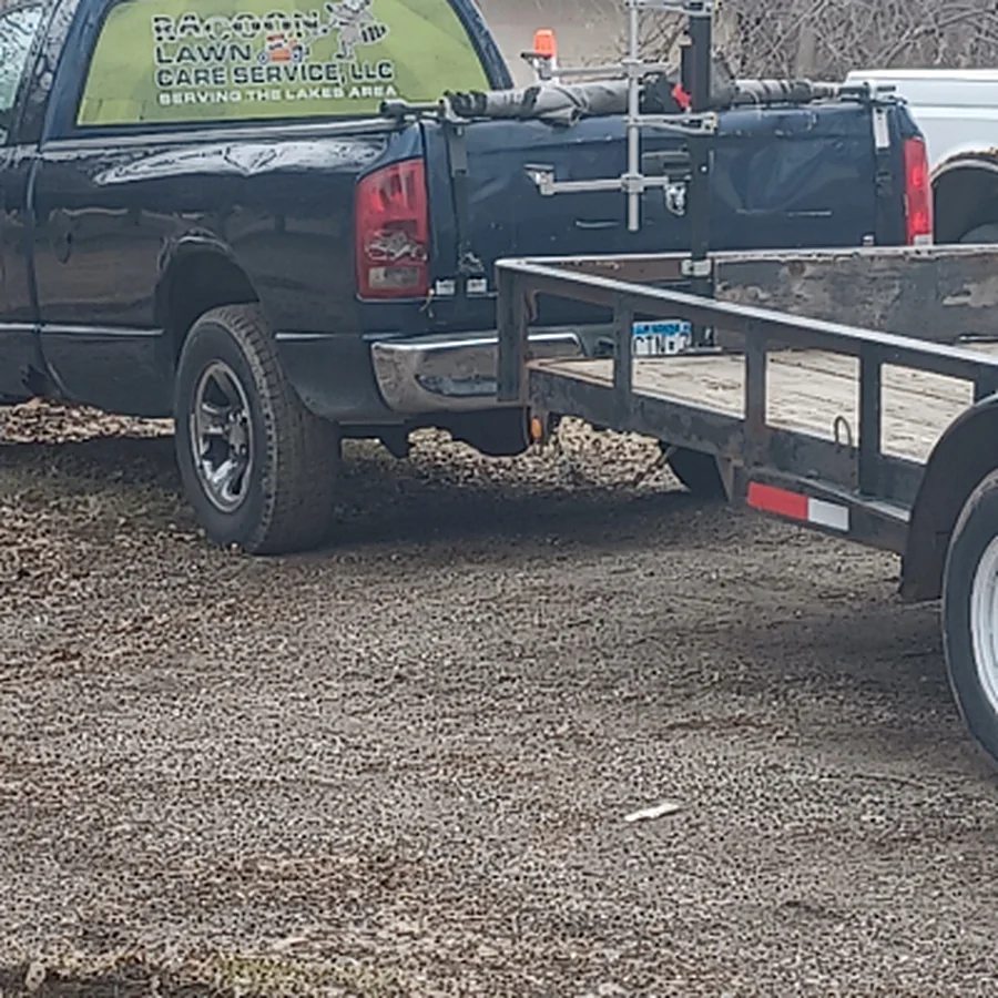 The Racoon Lawn Care Services, LLC truck and trailer, door decal reading Serving the Lakes Area